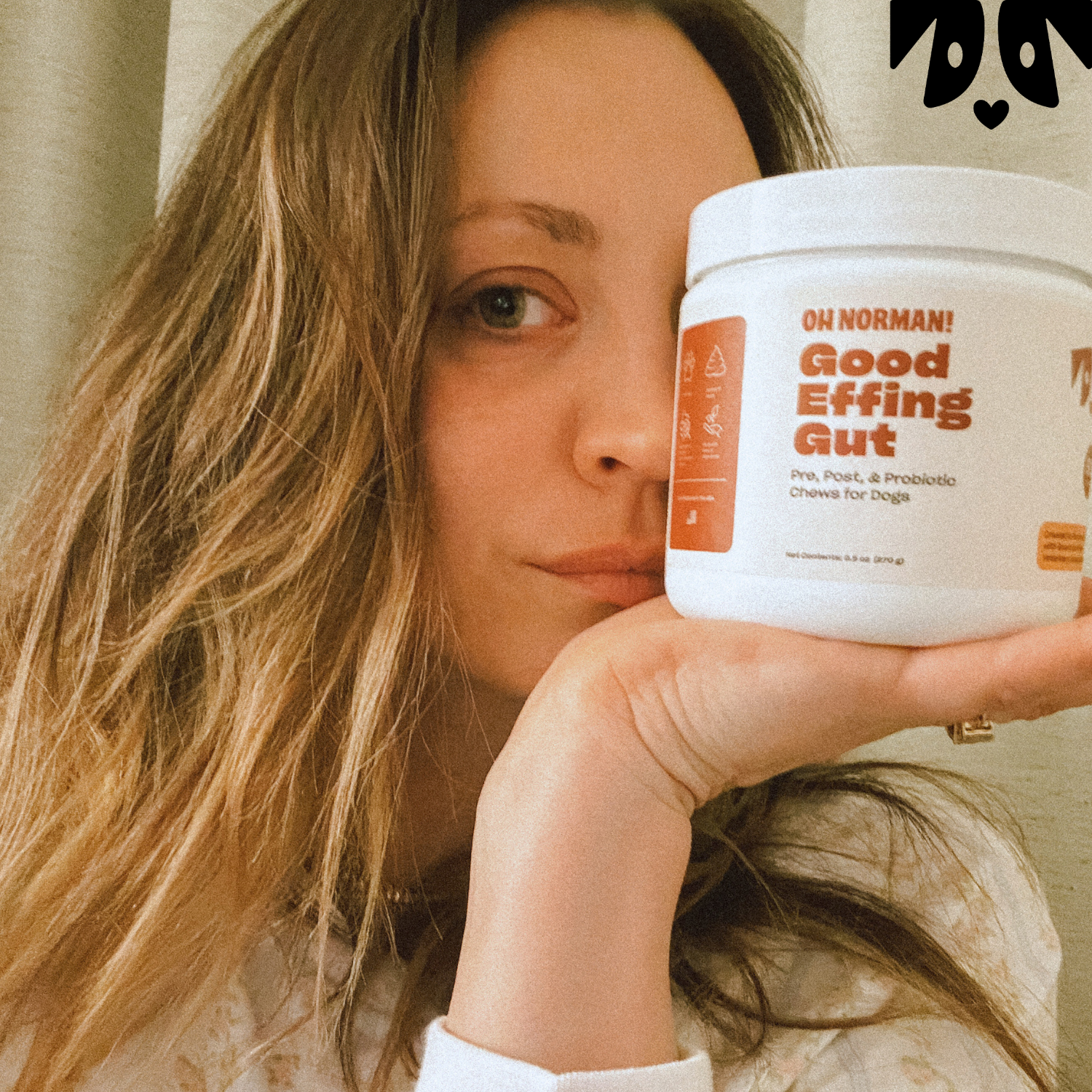 Actress Kaley Cuoco holding white jar labeled Good Effing Gut dog probiotic, close-up of face and product label