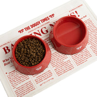 Red Oh-riginal bowl filled with food on a newspaper with headline 'BARKING' and text 'OH-RIGINAL RED BOWL'.