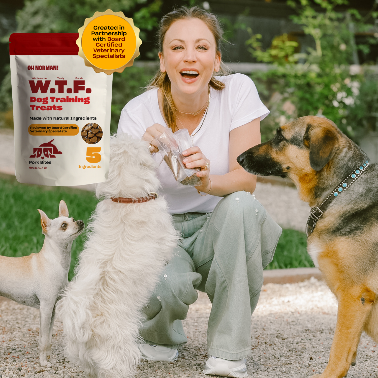 Kaley Cuoco holding a dog treat with three dogs sitting and standing around her outdoors