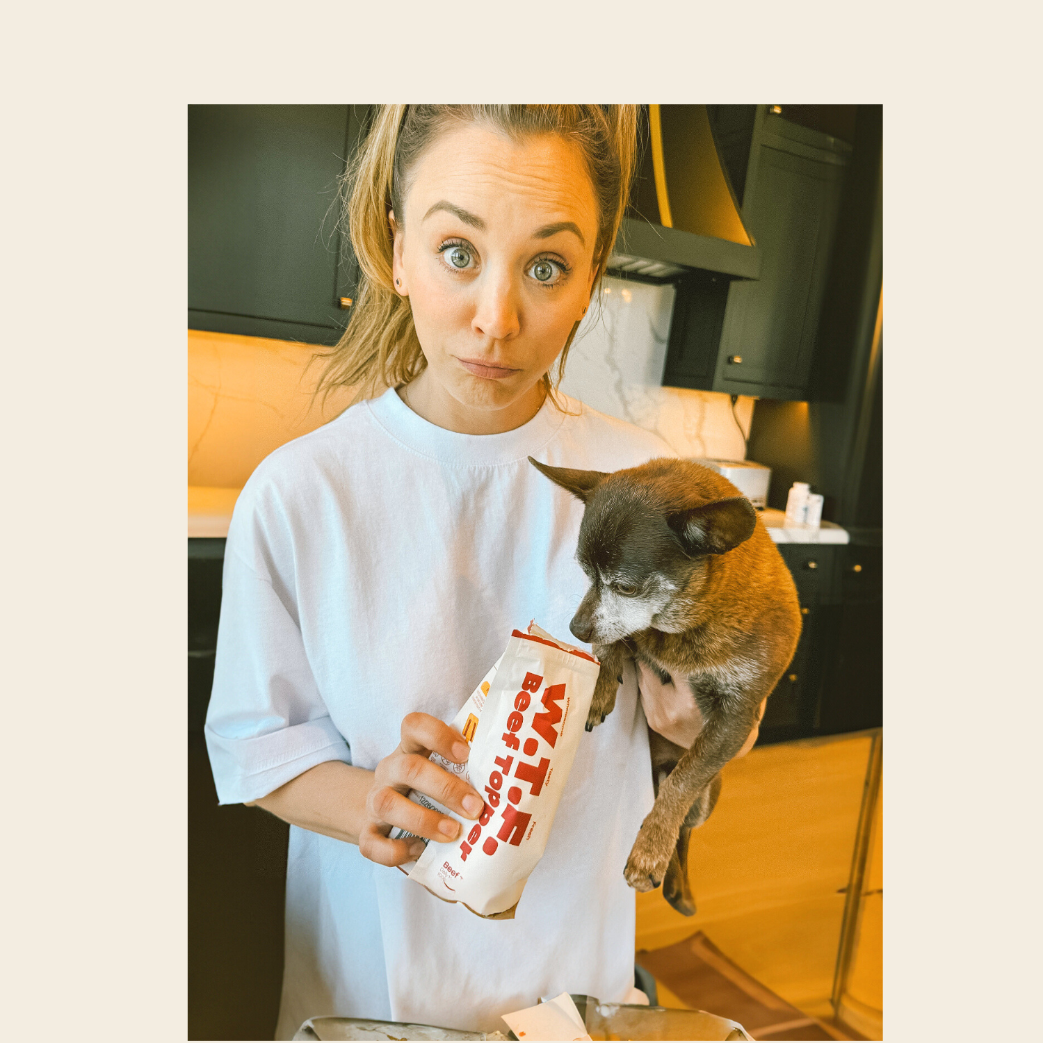 Kaley Cuoco holding a dog and a package labeled 'WTF Beef Topper'